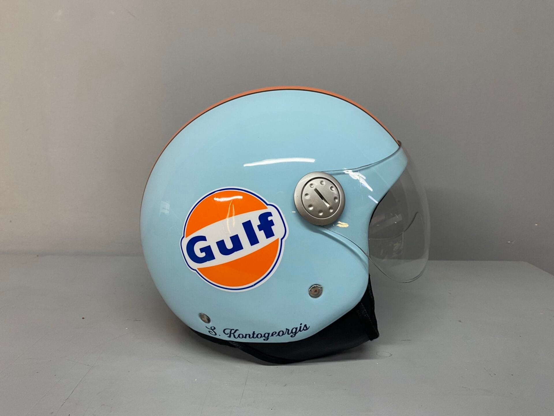 Πλευρική άποψη custom βαφής κράνους Gulf Racing με όνομα ιδιοκτήτη.